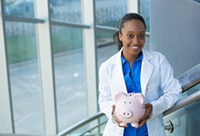 smiling dentist holding a pink piggy bank 